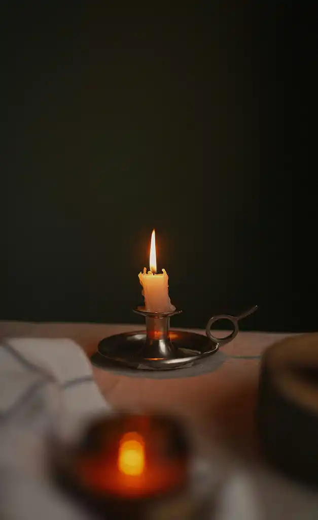 A candle on a table in a dimly lit room